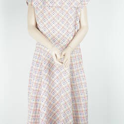 Checked, square-necked sleeveless dress made from white, yellow, blue and red cotton fabric.