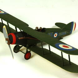 Dark green aeroplane model with red, white blue circles. Three quarter view from front left.