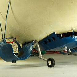 Detail of white model airship base and wheels. Blue nose and base brackets holding engines and fin-like wings.