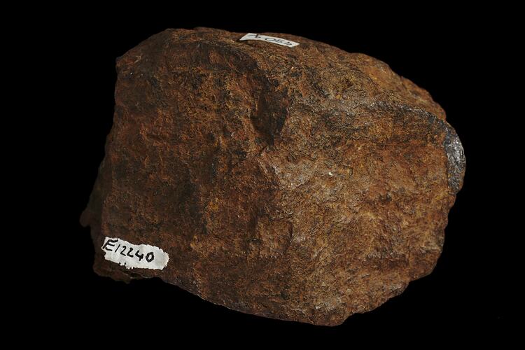 Rounded orange rock with hand written number.