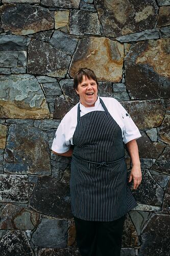 Chef leaning against stone wall.