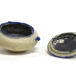 Side view of tiny white pot with lid off.
