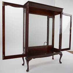 Wooden framed crystal cabinet. Glass doors and sides mirror at back. Front view, doors open.