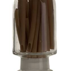 Clear glass jar containing brown long tube-shaped pasta.