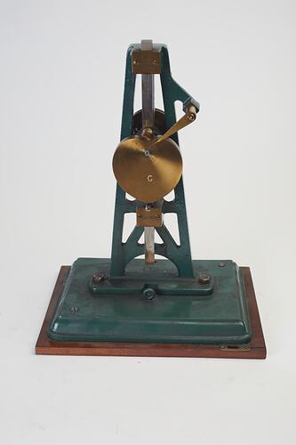 Metal model with green painted frame with metal heart shape and upright rod.