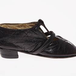 Miniature hand-sewn black leather shoe with strap and glass button fastener. Right profile.