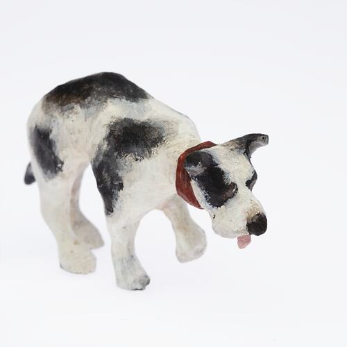Black and white dog figurine with red collar and tongue.