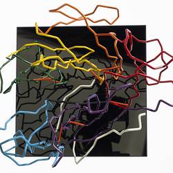 Red, orange, yellow, green, blue, purple and white coloured wires mounted on a black wooden base.