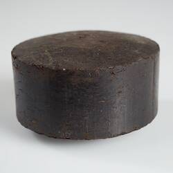 Disc-shaped dark brown briquette with flat sides.