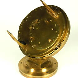 Three quarter view of gold metal chronometer.
