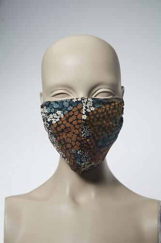 Face mask with floral design in brown, blue, black and white.