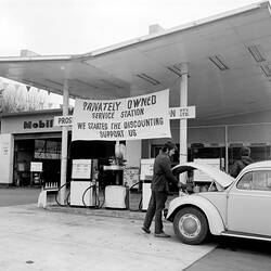 Negative - Attending to a Volkswagen 'Beetle' Motor Car in the Driveway of Prospect Hill Road Service Station, Camberwell, Victoria, 1971