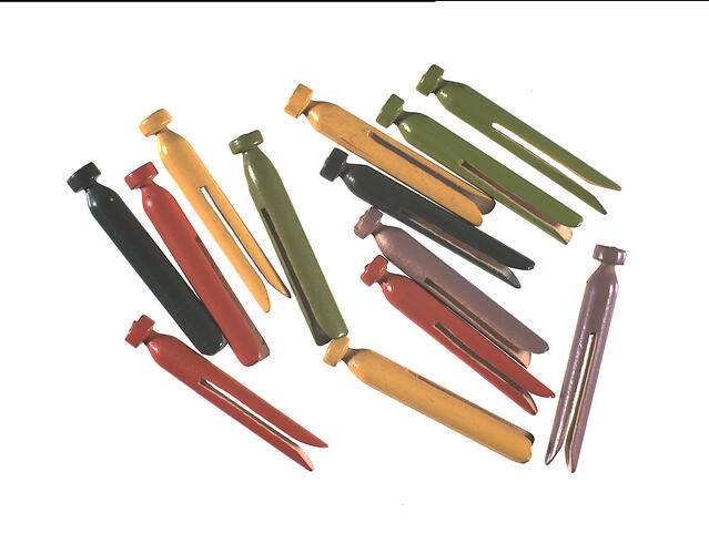 Wooden clothes pegs in light and dark green, yellow, red and mauve.