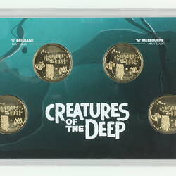 Four silver coins with sea creatures set in blue/green card. White printed text.