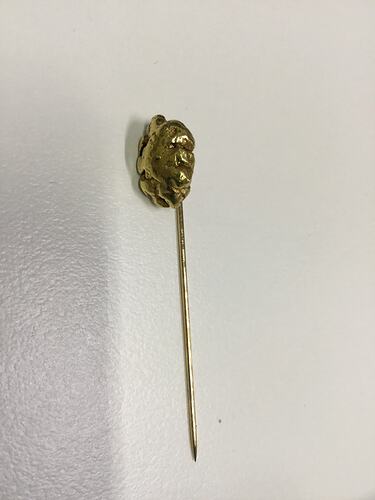Stick pin with small gold nugget at top.