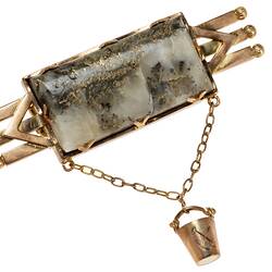 Triple bar brooch with central quartz and gold specimen with small gold bucket attached via chain.
