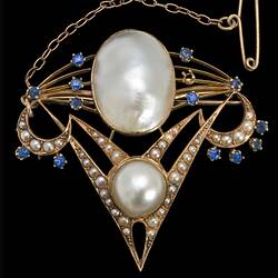 Delicate gold inverted triangle brooch with two main pearls framed by seed pearls and blue paste. A fine gold chain and pin extend from top left corner.