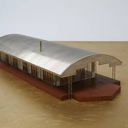 Model of a house with an arched roof, corrugated iron and wide expanses of glass.