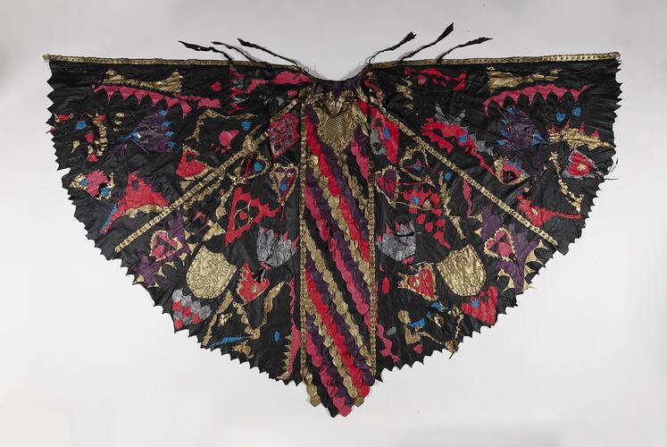 Black leather cloak with coloured leather scales and shapes joined with bronze metal studs.