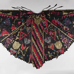 Black leather cloak with coloured leather scales and shapes joined with bronze metal studs.