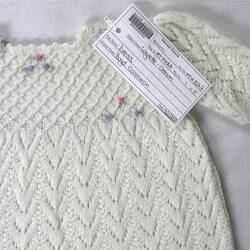 Cream wool knitted child's dress, rosebud motifs.