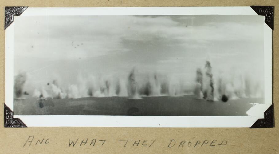 Multiple explosions rising from the ocean in middleground, group of plains in left background.