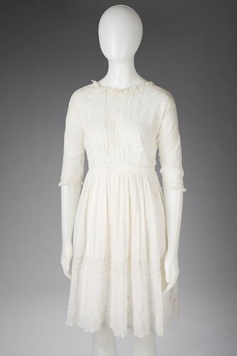 White cotton and lace girls dress. Mid-length sleeves and mid thigh skirt.