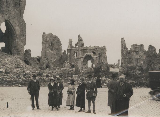 A group of men and women posing in front of the ruins of a building.