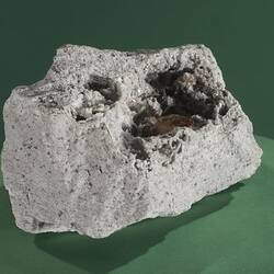 White block of rock with clear pink crystal on surface.