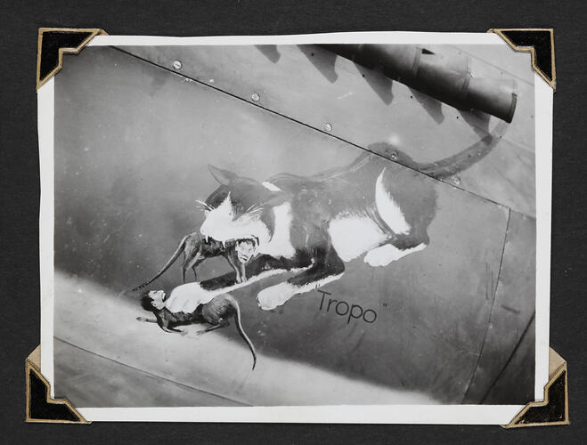 Painting on side of aeroplane of cat attacking two mice with human heads.
