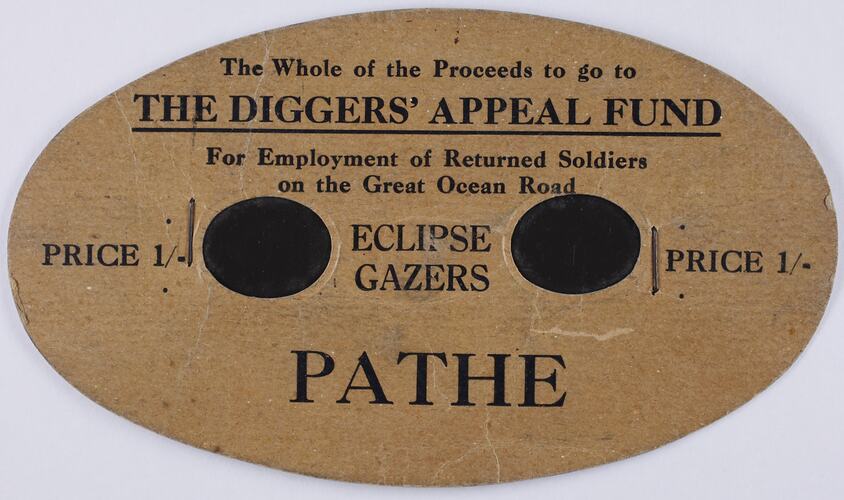 Oval shaped brown card with black printed text and two black circles in centre.