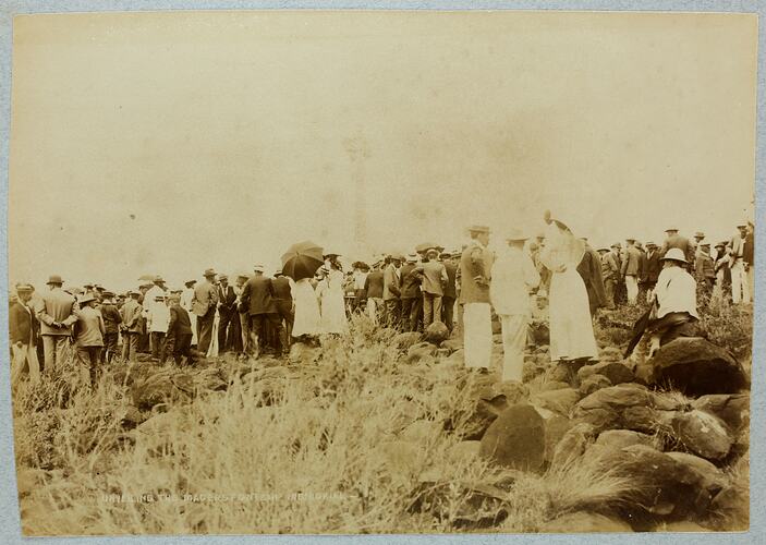Group of men and woman in rocky slope, backs facing camera.