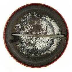 Back of round rusted badge with pin.