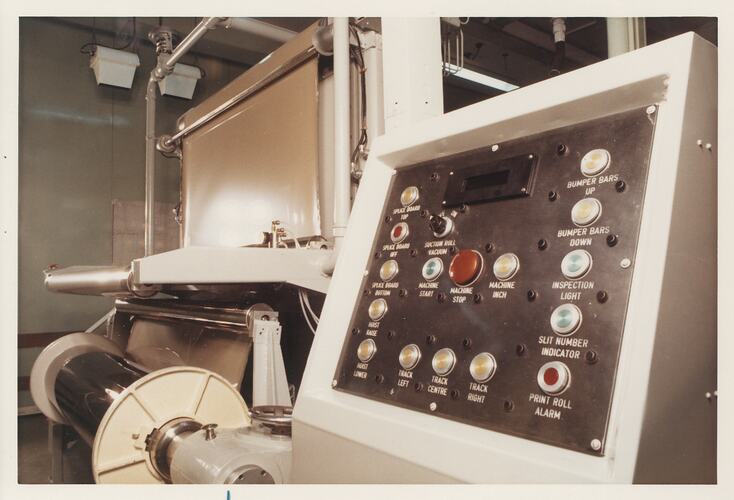 Machine control panel with roller components in background.