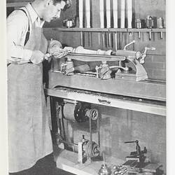 Photograph of man working at lathe.