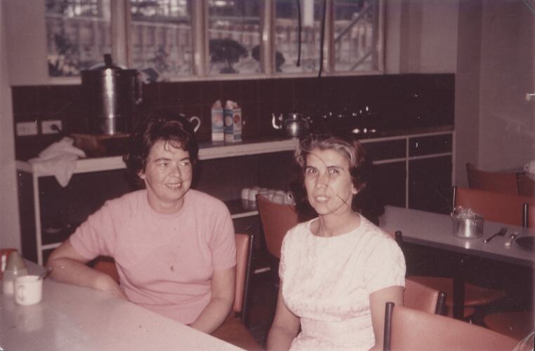 Two women seated at lunchroom table.
