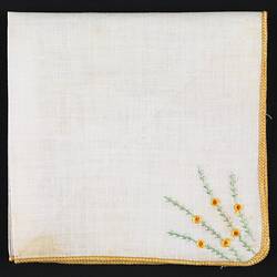 Folded handkerchief with embroidered spray of flowers.