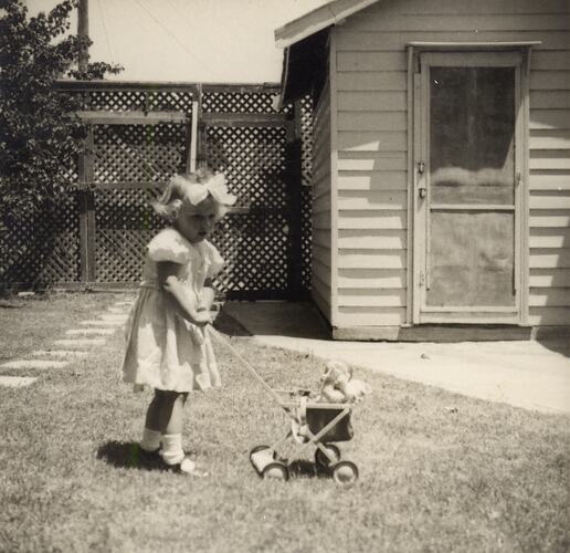 Susan Leech Pushing Toy Pram in Her Back Yard, Frankston, circa 1954
