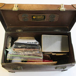 Brown suitcase with lid open showing contents.