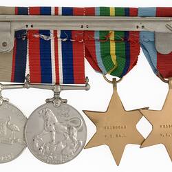 Group of four metals with ribbons joined together by metal pin.