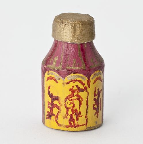 Miniature red and yellow canister from a doll's house.