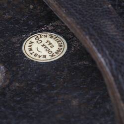 Camera body, leather covered. Detail of maker's mark on top. Ivory circle with text.