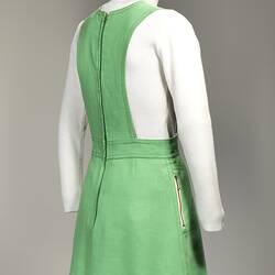 Back angle view of lime green linen mini pinafore dress with zip.