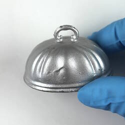 Oval silver toy cloche, side view.