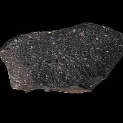 Black rock with pale speckles.