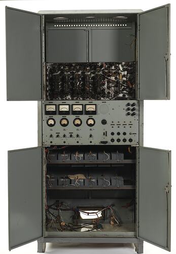 Grey metal cabinet, four open doors. Contains circuit boards, wires. Central section has dials, switches.