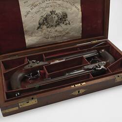 Two guns in wooden case, burgundy lining. Has seven sections.