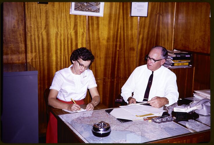 Man and a woman sitting at a desk.