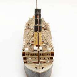 Cardboard model of passenger steamship. View of front bow section with central row of four funnels.