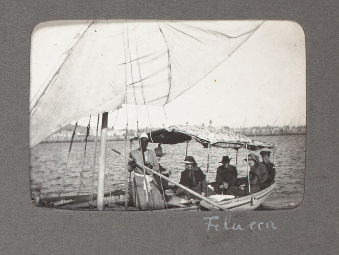 Boat on river with sails and passengers.